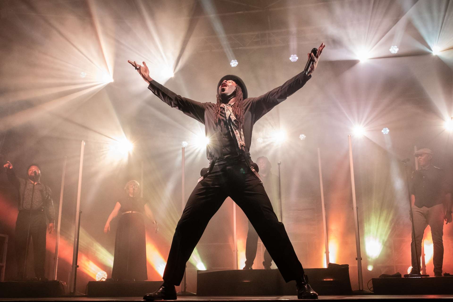 Chanteur levant les bras lumière de scène